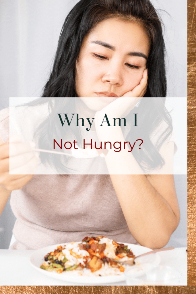 Woman looking sad with food, with the words 'why am I not hungry?'. what to do if you don't feel hungry